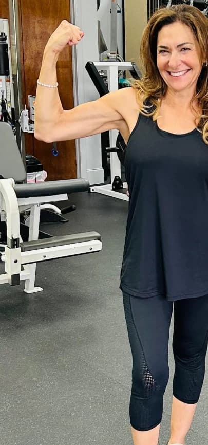 After: the same client, flexing her arm in a gym